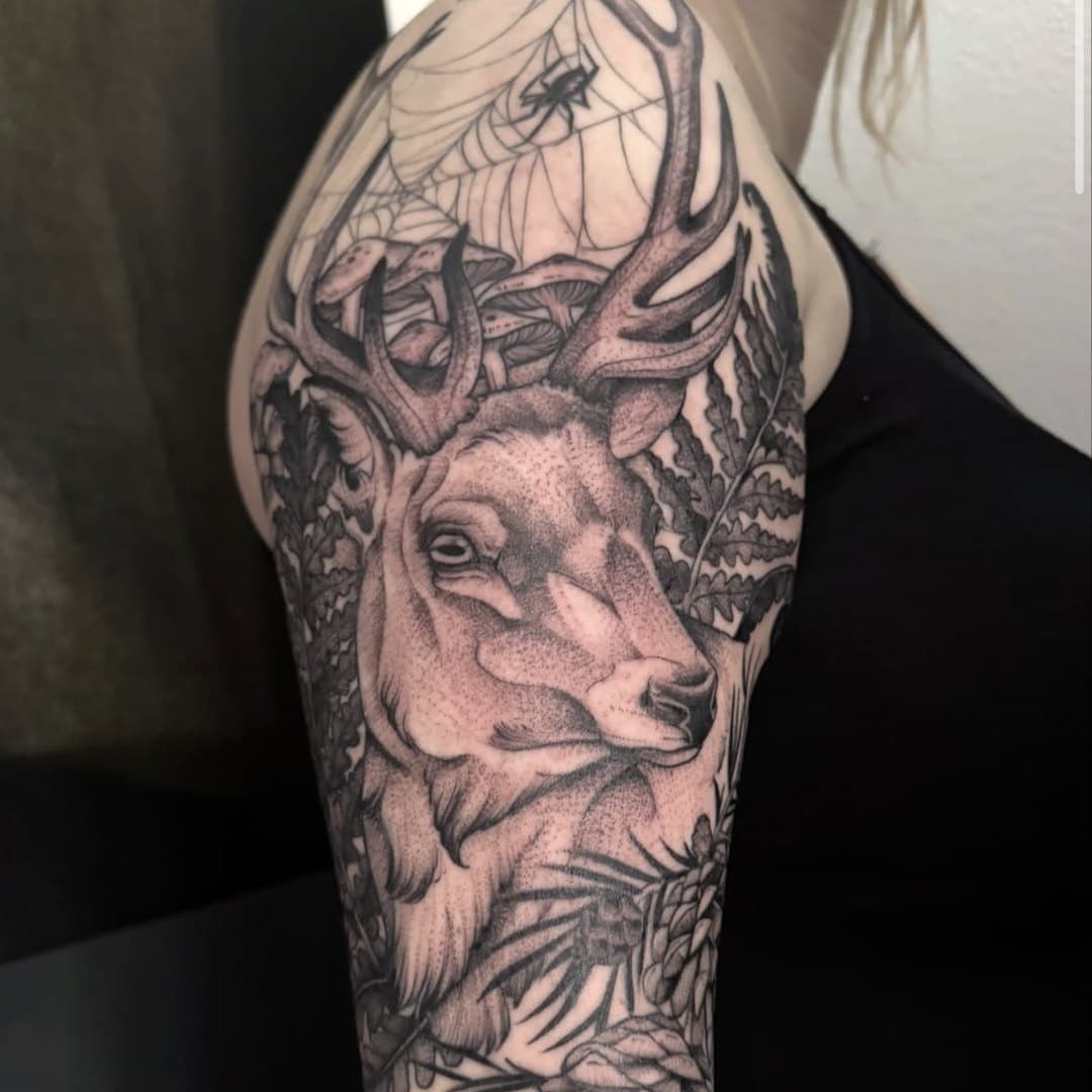 Hjort i black & grey med blommor på överarm av Julia Landehag, Zoi Tattoo House Malmö