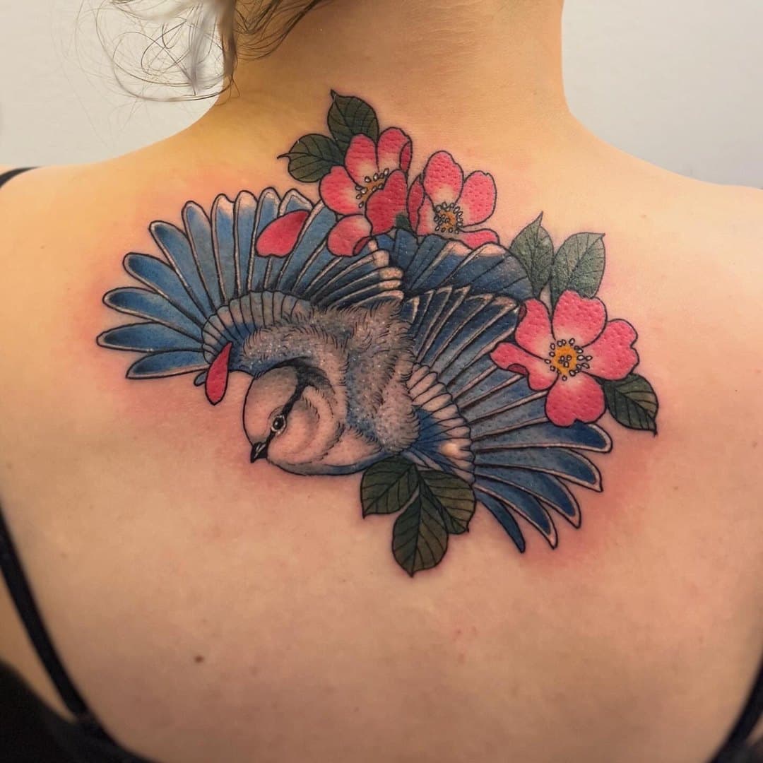 Färgstark fågel med röda blommor på övre rygg av Julia Landehag, Zoi Tattoo House Malmö